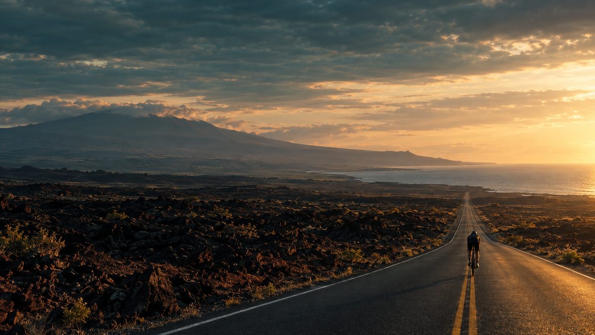 A lone triathlete on a time-trial bike riding a straight highway through black lava fields on Hawaiʻi's Big Island at first light