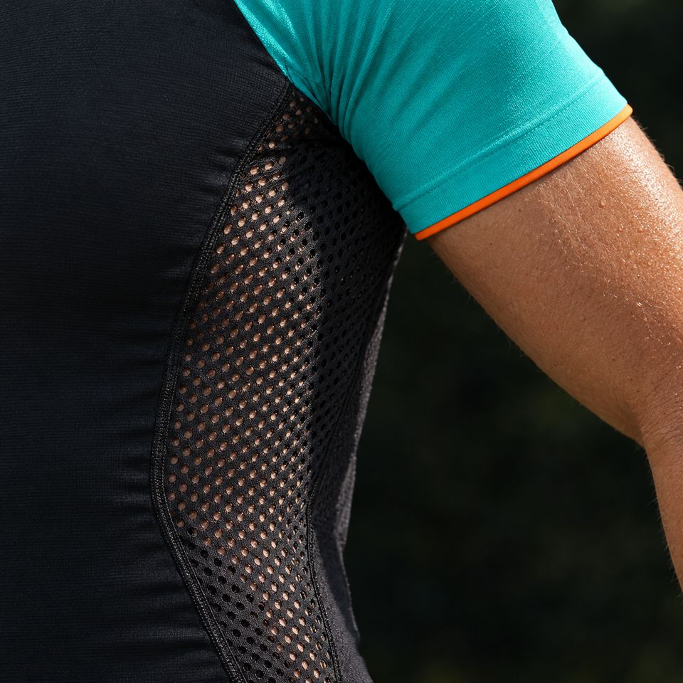 Concept render close-up: a black perforated mesh side panel under the arm, and a teal sleeve with an orange hem ending above the elbow.